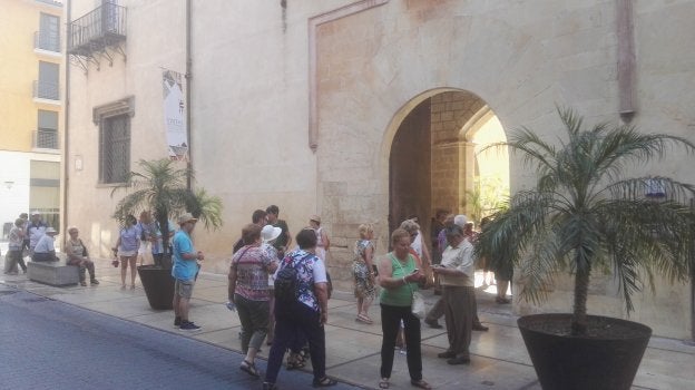 Una veintena de turistas esperando ayer por la mañana a la entrada del Palau Ducal de Gandia antes de comenzar la visita. / lp