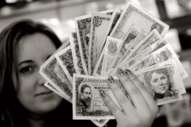 Pesetas. joven muestra billetes de veinticinco, quinientas y mil pesetas