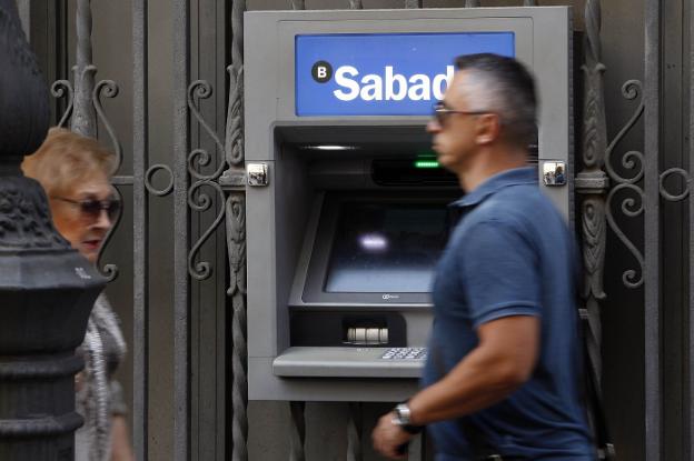Viandantes
pasando junto
a un cajero del
Sabadell. / irene marsilla