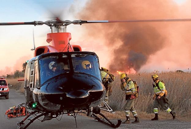 Bomberos suben a un helicóptero durante el incendio de Torreblanca. / LP