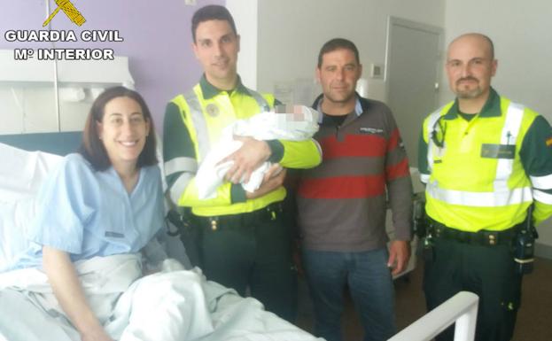 El recién nacido, con sus padres y los guardias civiles que los asistieron, posan en el hospital La Fe. /G. C.