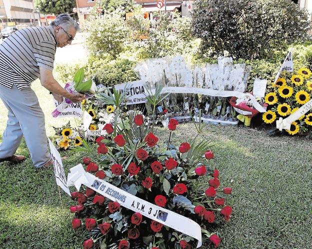 Un hombre coloca flores en recuerdo de las víctimas. / efe