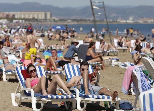 Una multitud de personas llena las hamacas y el arenal de la Malvarrosa, ayer, por la tarde, en una jornada a 30 grados. / m. molines
