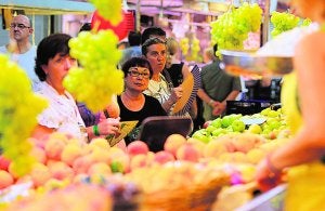 Compradores esperan su turno ante un puesto de fruta en el Mercado Central. :: JUANJO MONZÓ/