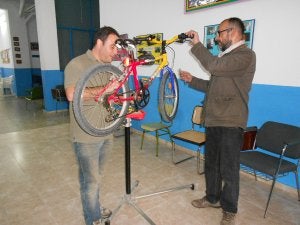 Dos voluntarios de la iniciativa reparan una de las bicicletas donadas al proyecto. ::
A. D./