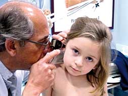 Un pediatra inspecciona el oído de una niña./