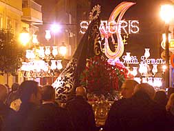 Procesión del Viernes de Dolores, la única que ha salido a la calle estas Fallas, con un monumento al fondo./