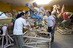 Operarios del taller del artista Julio Monterrubio, ayer, tras descargar de un tráiler parte de las figuras que componen el monumento fallero de Nou Campanar, las guardan en una planta baja./
