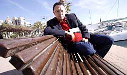 El escritor Luis Leante en el Paseo del Puerto de Alicante, ayer al mediodía, con su nueva novela La luna roja, de la editorial Alfaguara./