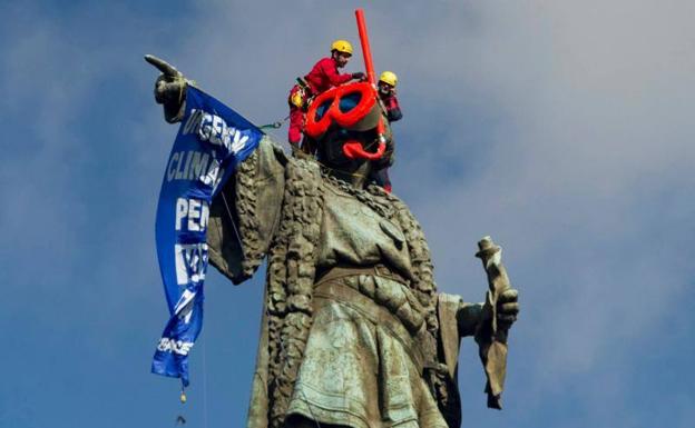 Dos activistas de Greenpeace colocan unas gafas de buzo a la estatua de Colón en Barcelona