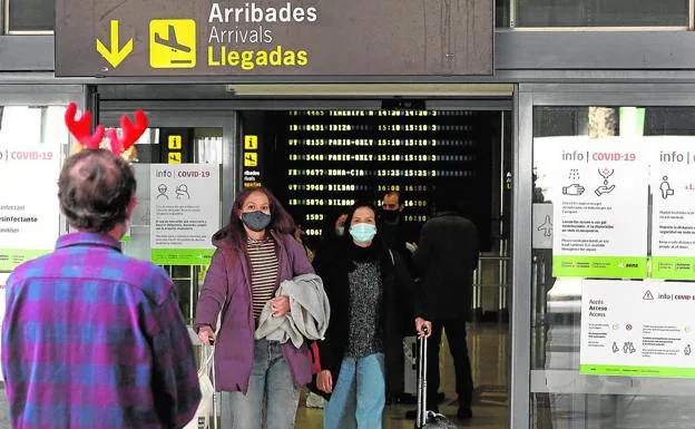 Un hombre con un tocado navideño espera ayer a las puertas del aeropuerto de Valencia la salida de un pasajero./jesús signes