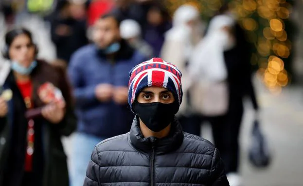 Un joven camina por la calle Oxford, en el centro de Londres, con un gorro con la bandera del Reino Unido./AFP