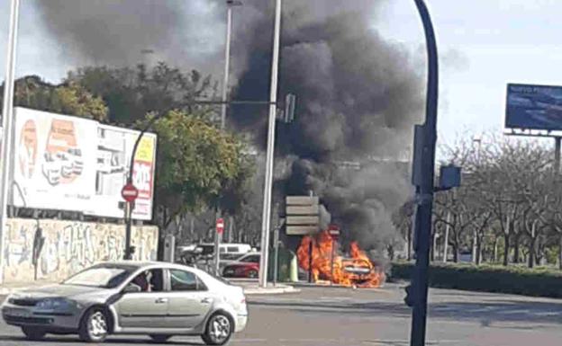 Espectacular incendio de un coche en la avenida Tres Cruces de Valencia cuando viajaban una mujer y dos niños en el interior