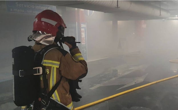 Los bomberos extinguen un incendio en un coche en el aparcamiento del centro comercial Gran Vía