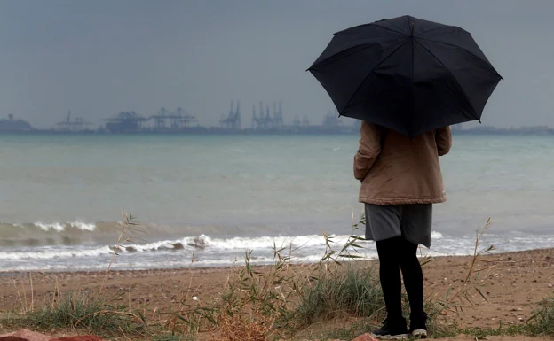 Una mujer mira el mar durante un episodio de lluvia. 