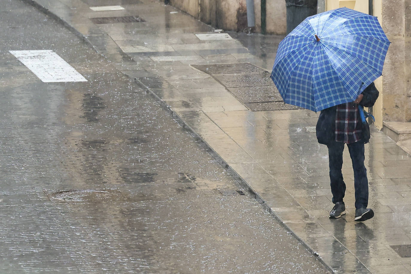 Una persona se protege de la lluvia a primera hora de la mañana en Valencia.