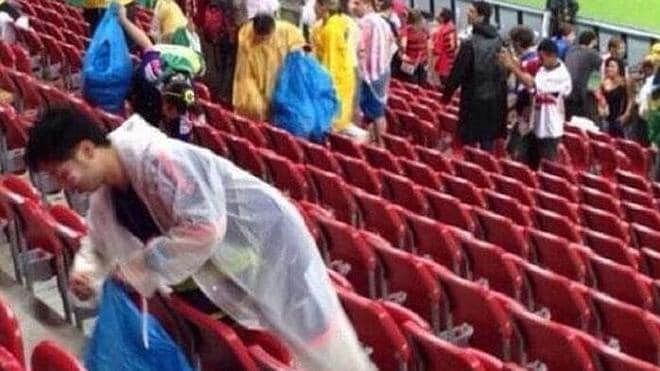 Los aficionados japoneses limpian el estadio tras finalizar el partido con Costa de Marfil