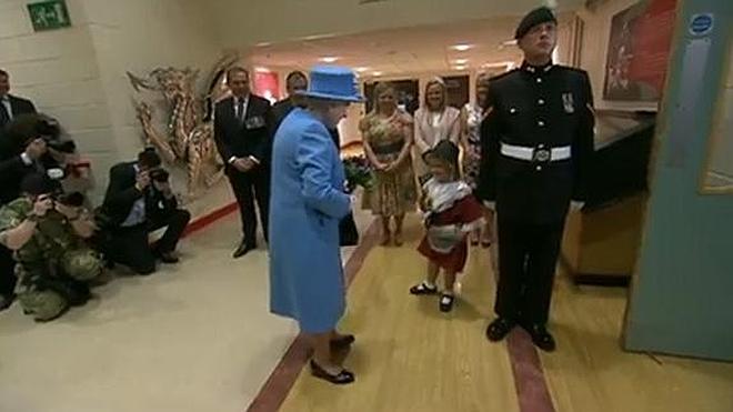 Un soldado de la Reina británica golpea a una niña al hacer el saludo