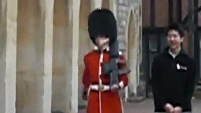 Un guardia real británico apunta con su fusil a un turista